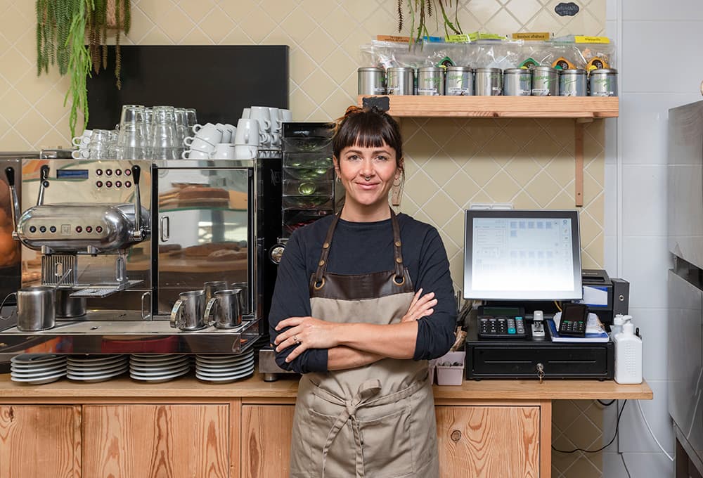 Barista standing in front of a coffee machine and register